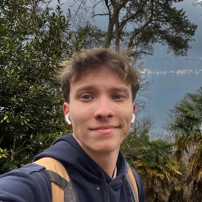 Alexander Hiermann, outdoors in front of a lake and wooded hills.